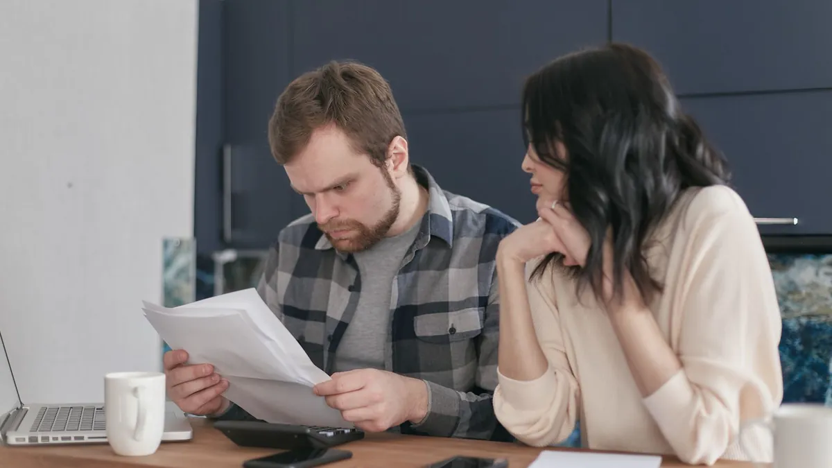 Zwei Erwachsene lesen am Tisch gemeinsam Unterlagen